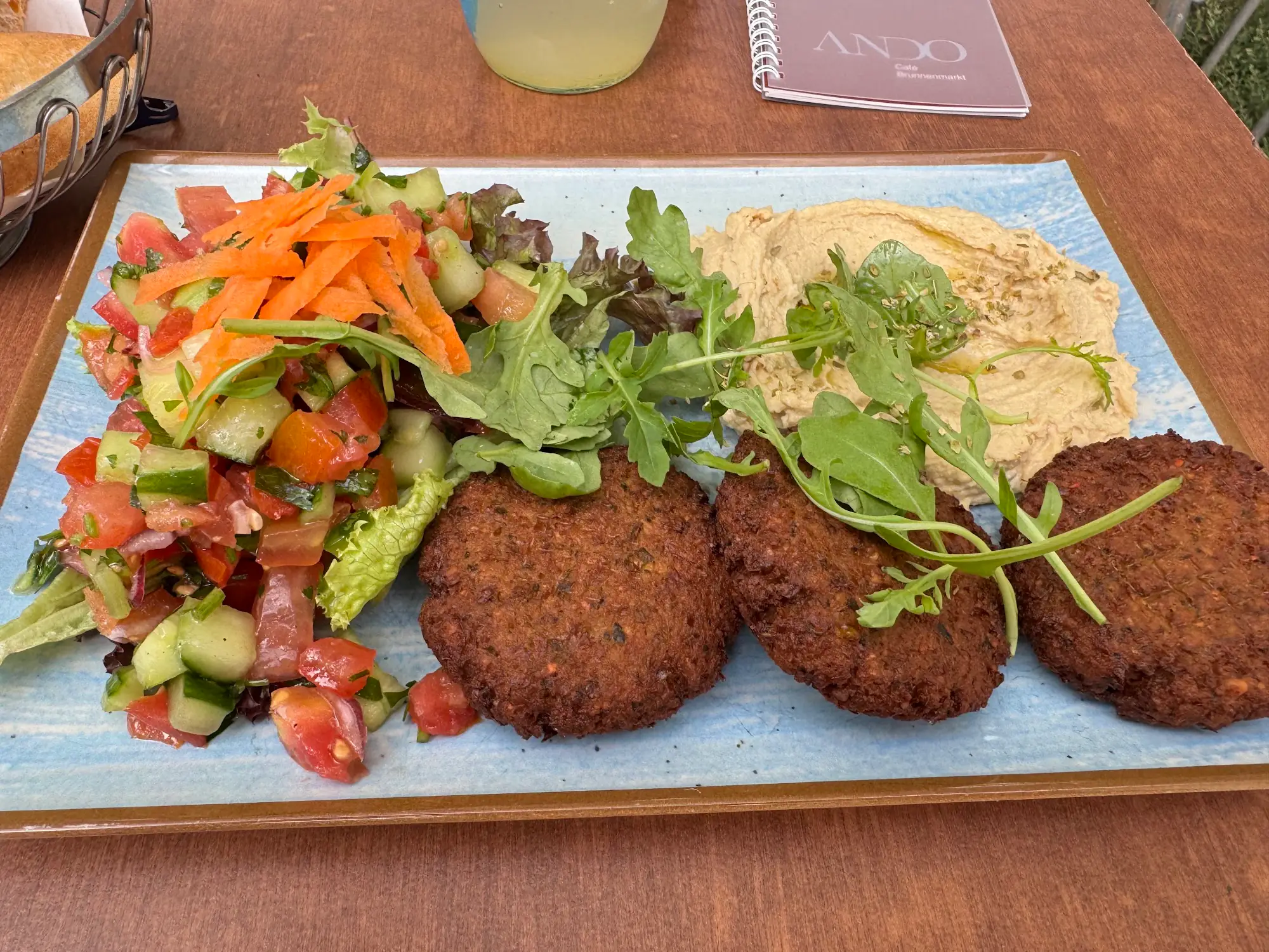 Falafel mit Hummus, Salat und geriebenen Karotten auf hellblauem Teller